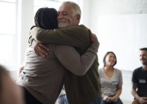 Two elderly people hugging and supporting each other