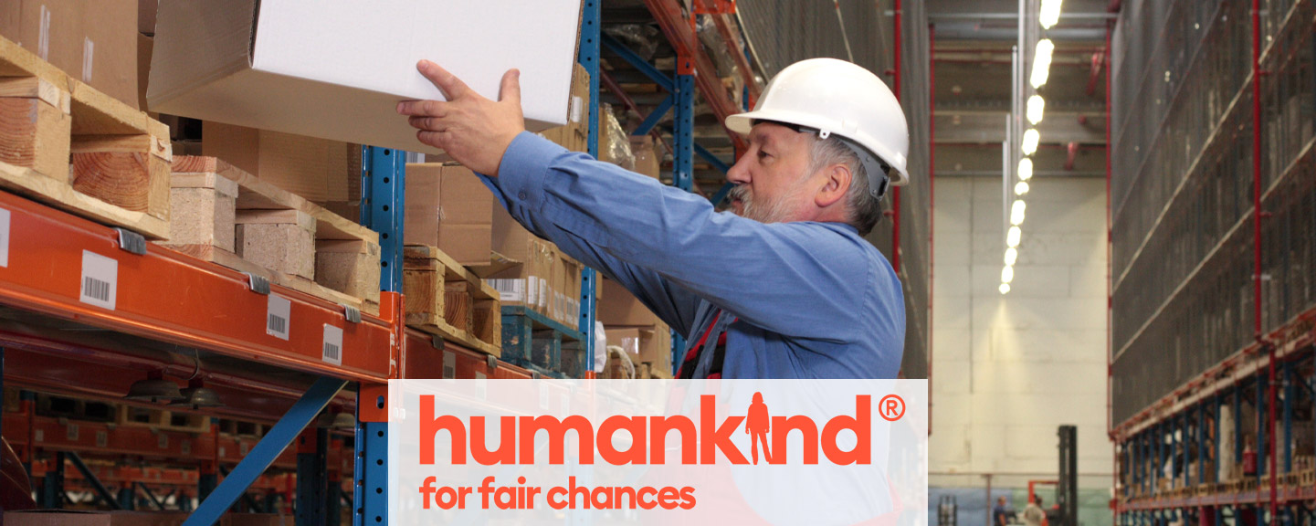 A worker lifts boxes onto a shelf in a warehouse