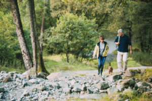 Senior couple are hiking through the Lake District together with their pet dog.