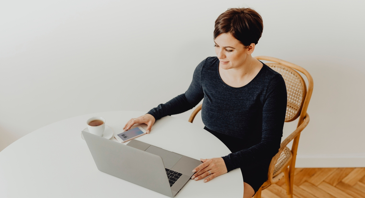 Woman looks at laptop and mobile app