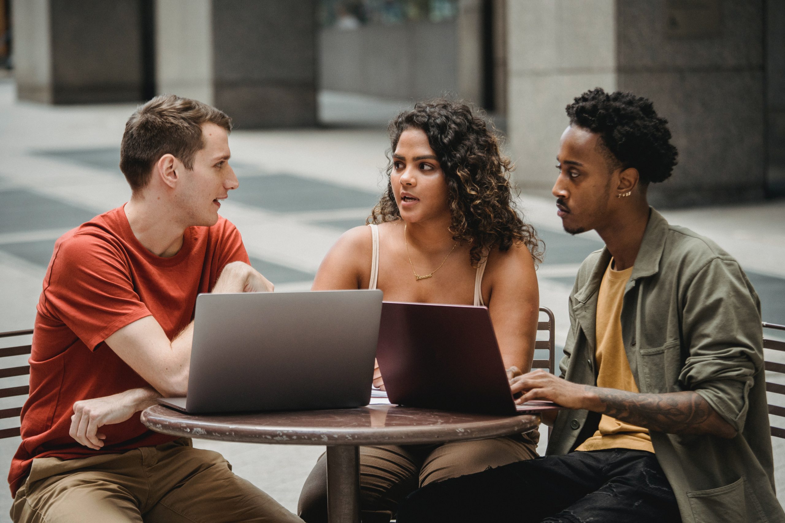 Three young people use laptops