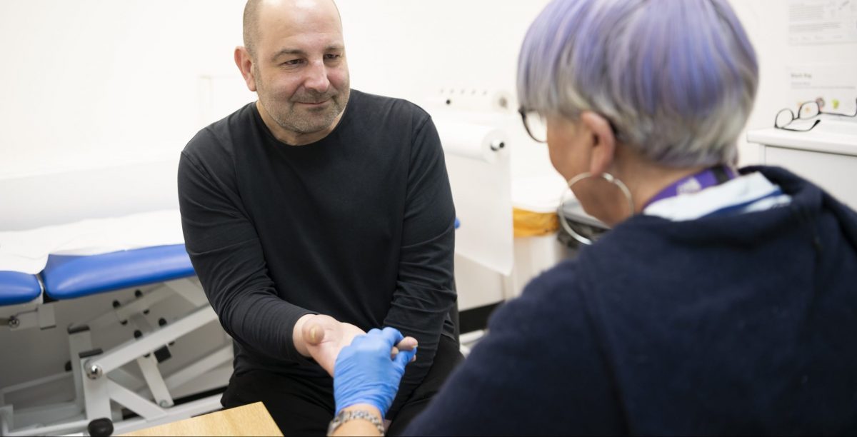 A person receiving a finger prick test from a health professional to check for hepatitis C