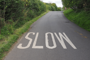 A road with the words "slow' painted on it