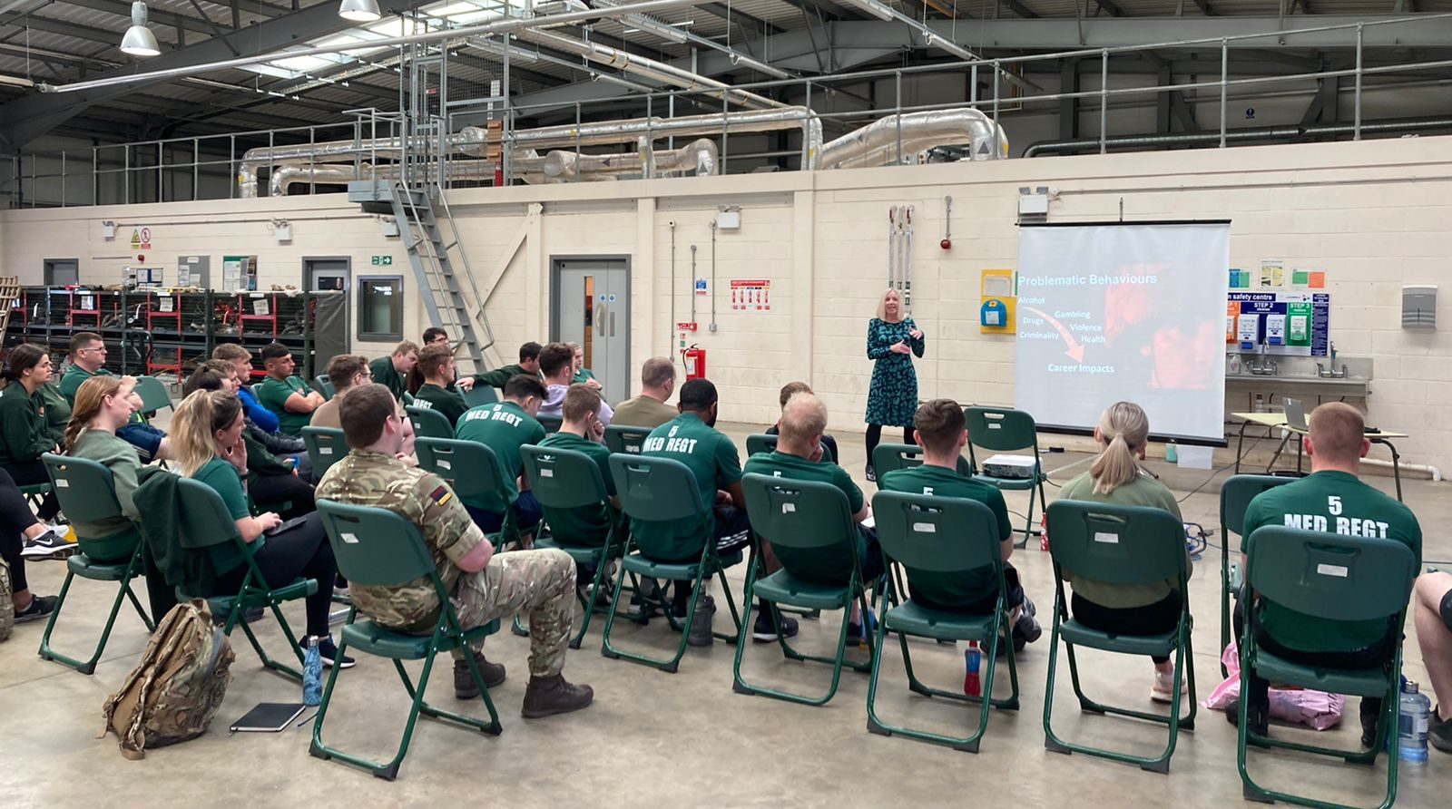 A woman leads a presentation on the harms of alcohol and gambling with army personnel