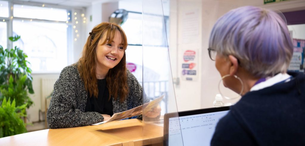 A woman talking to another woman at a reception desk